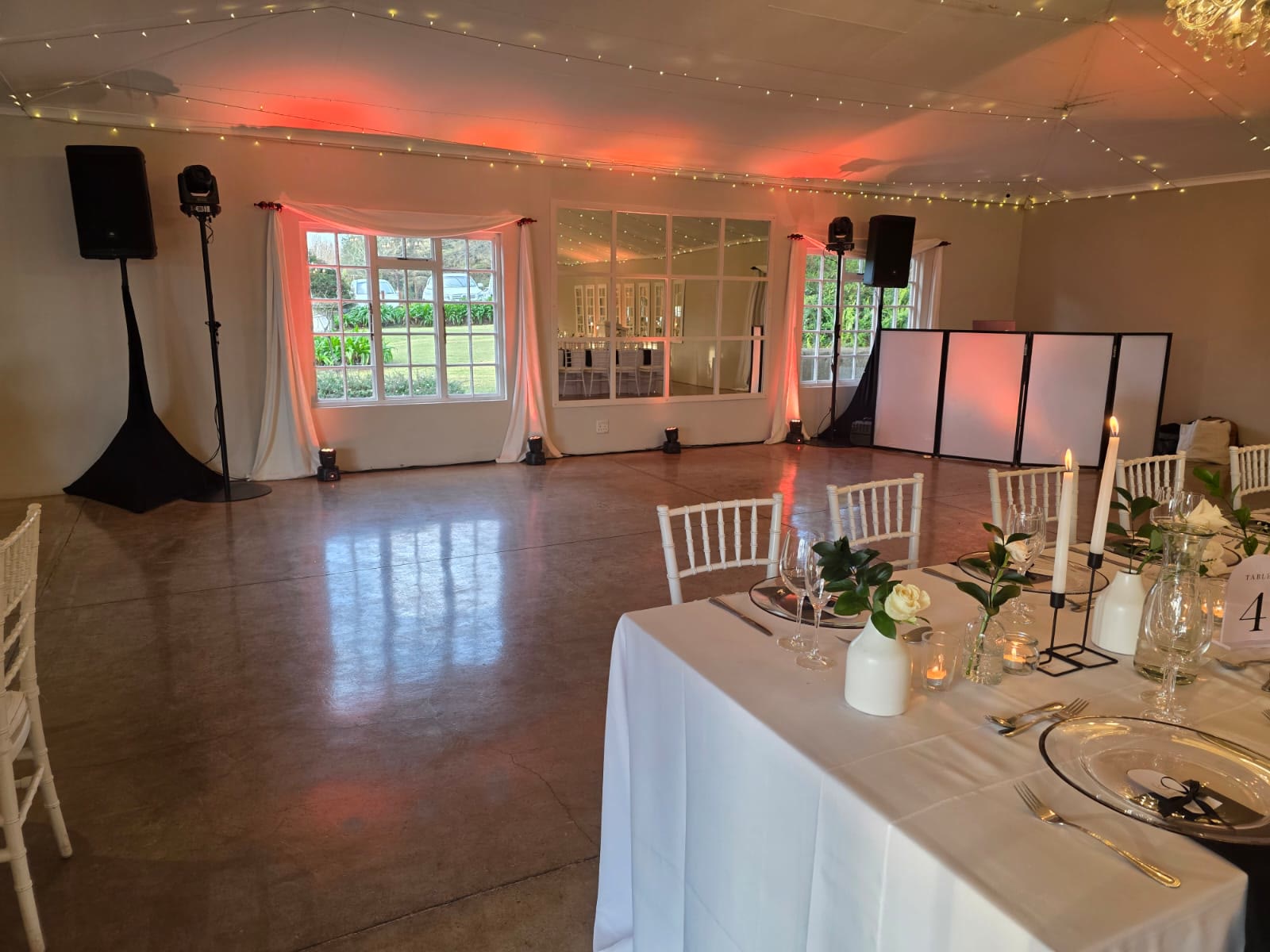 Empty dance floor at Providence wedding venue with professional sound system setup, elegant pink and coral uplighting along walls, white French doors, table settings visible, ready for reception celebration at KZN Midlands country estate