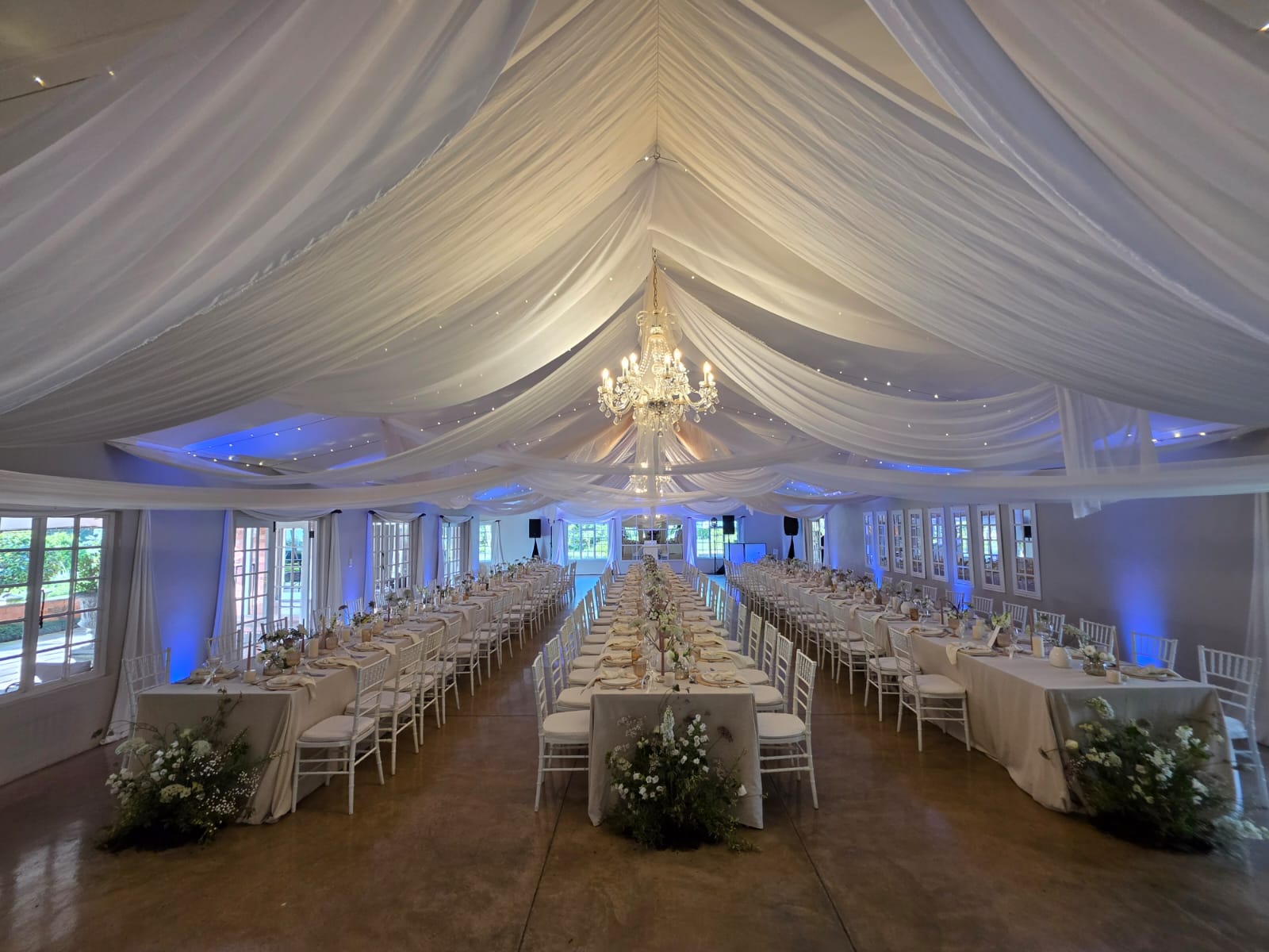 Providence reception hall with long tables and blue uplighting creating atmospheric wedding dinner ambiance in KZN Midlands